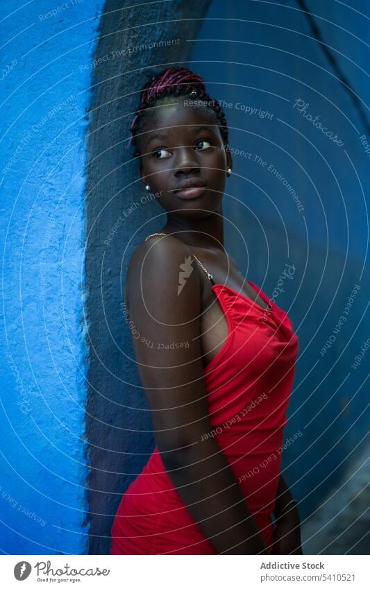 African American woman in red dress thoughtful pensive wall style trendy fashion outfit think lean calm dreamy stand personality braids lean on model modern