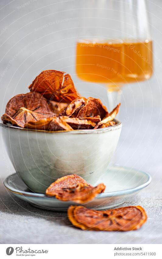 Slices of dried apples in bowl near glass of juice slice fruit plate ceramic blur blurred background many taste tasty yummy delicious healthy nutrient nutrition