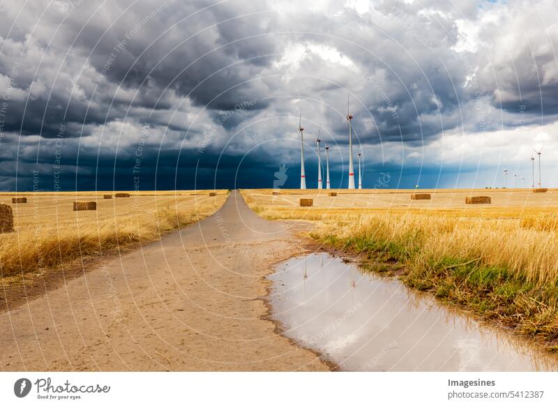 Thunderstorm. Wind farm and grain fields with hay bales. Storm over the field. Dark storm clouds moving in. Farmland with wind turbine wind farm Grain fields