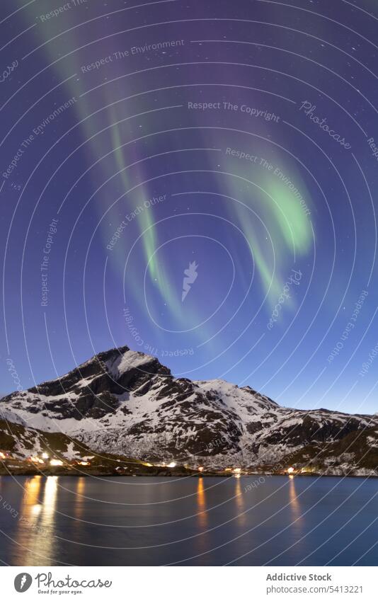 Amazing view of northern lights over snowy mountains and illuminated houses in night picturesque polar sky winter aurora highland ridge evening aurora borealis