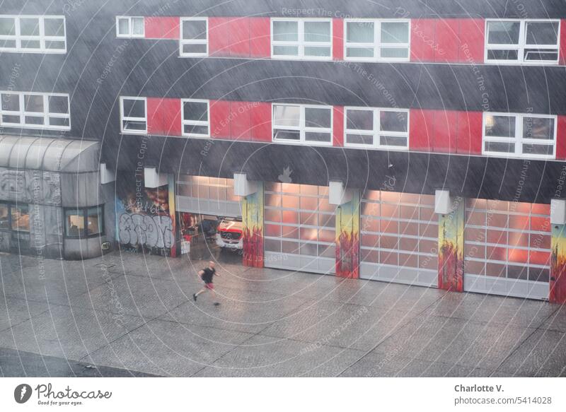 Summer thunderstorm in front of the fire department Rain summer thunderstorms Fire department Bad weather Exterior shot Wet Weather Colour photo one person