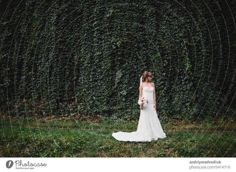 Beautiful bride in fashion wedding dress on natural background.The stunning young bride is incredibly happy. Wedding day. A beautiful bride portrait. flower