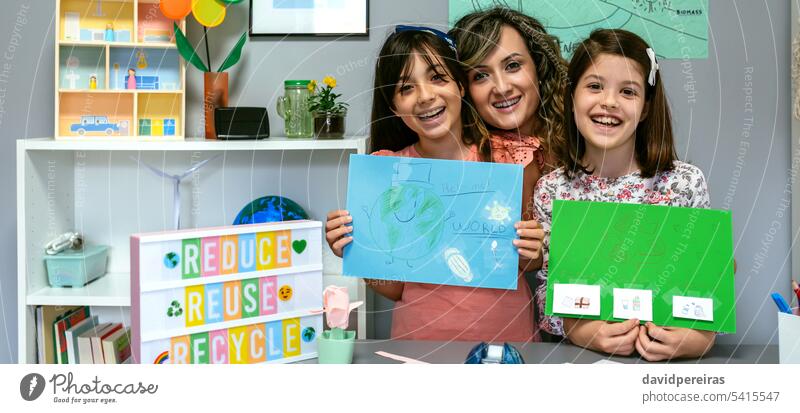 Teacher in classroom looking at camera next to students showing colorful ecological drawings happy female teacher smile poster panoramic web header panorama