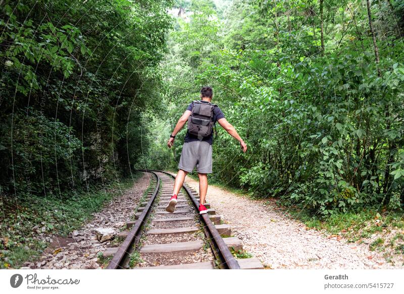 young male tourist walks on the railway in the jungle of thailand adventure backpack climate fitness forest freedom fresh go green health hiking journey