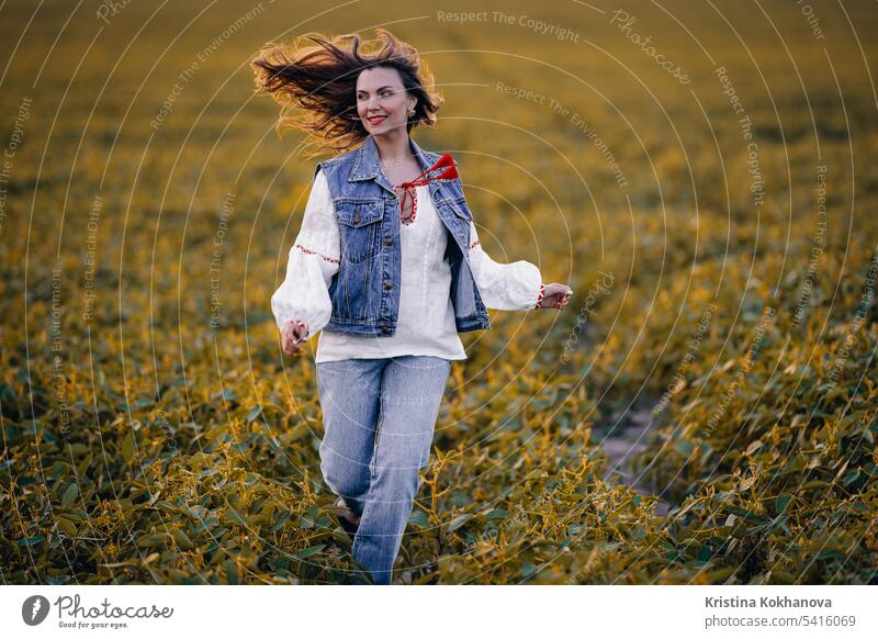 Happy woman running in green field. Young lady in white embroidery ethno shirt. happy ukrainian young beautiful beauty female girl person stylish portrait