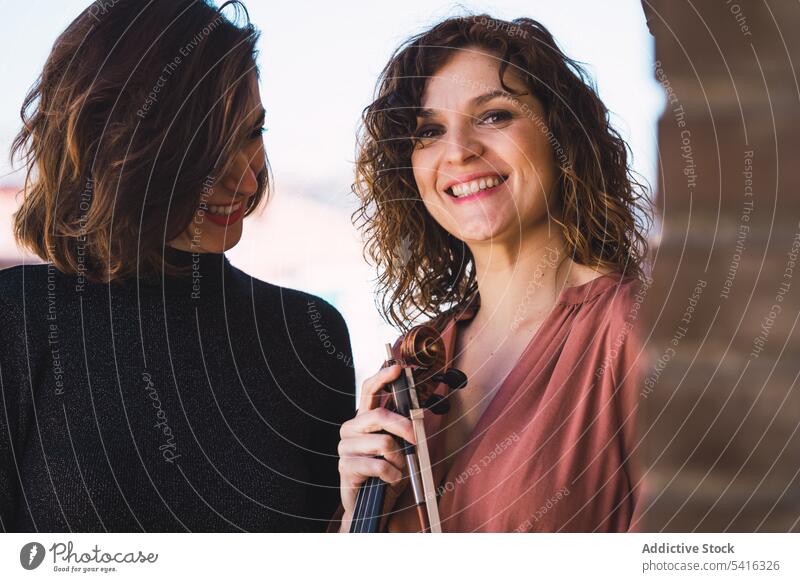 Young smiling women with violin on balcony woman musician young elegant friend instrument cheerful art sound playing performance female melody violinist