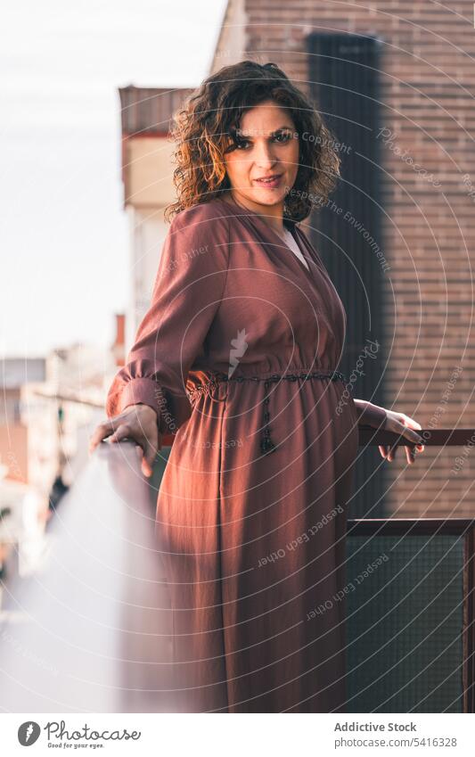 Attractive woman on balcony attractive young curly hair beautiful city urban female positive lifestyle relax casual leisure summer home elegant fashion pleasure