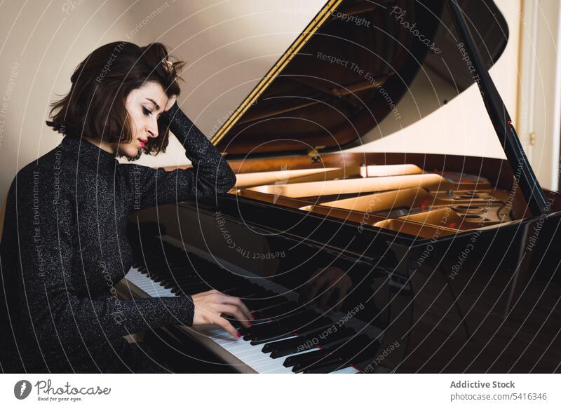 Young woman playing on piano musician young slim elegant room pianist instrument keyboard art sound performance female melody classical closed eyes harmony