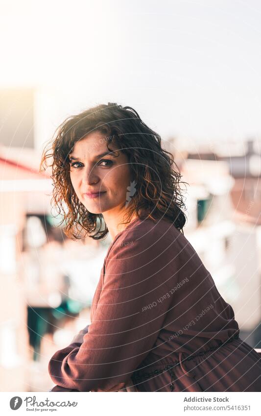 Attractive woman on balcony attractive young curly hair beautiful city urban female positive lifestyle relax casual leisure summer home elegant fashion pleasure