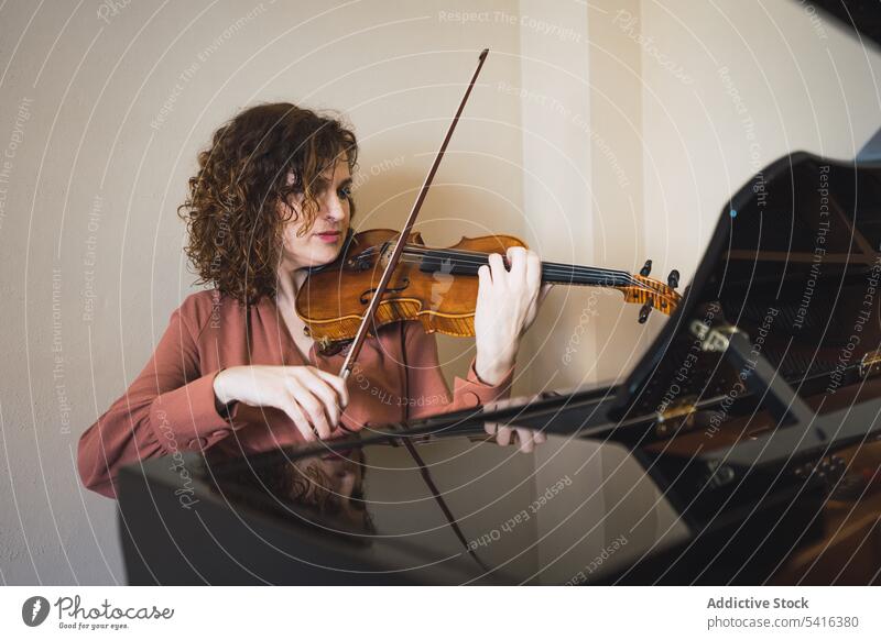 Pregnant woman playing on violin near piano in room pregnant musician attractive young curly hair beautiful closed eyes female belly sitting lifestyle relax