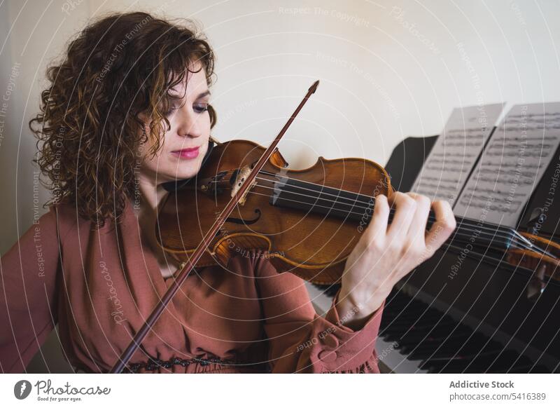 Pregnant woman playing on violin near piano in room pregnant musician attractive young curly hair beautiful closed eyes female belly sitting lifestyle relax