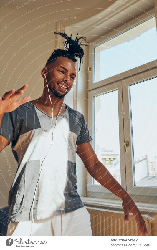 Cheerful ethnic male listening to music man hairstyle cornrows braided earphones dance thumbs up young african american person handsome positive attractive