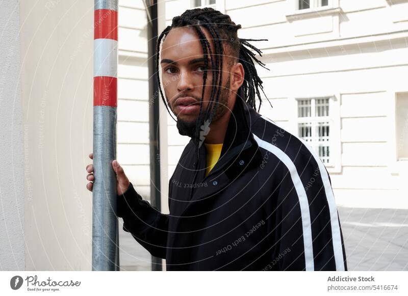 Ethnic male standing outside man ethnic braided hair young african american person handsome attractive pensive thoughtful serious bearded stylish trendy