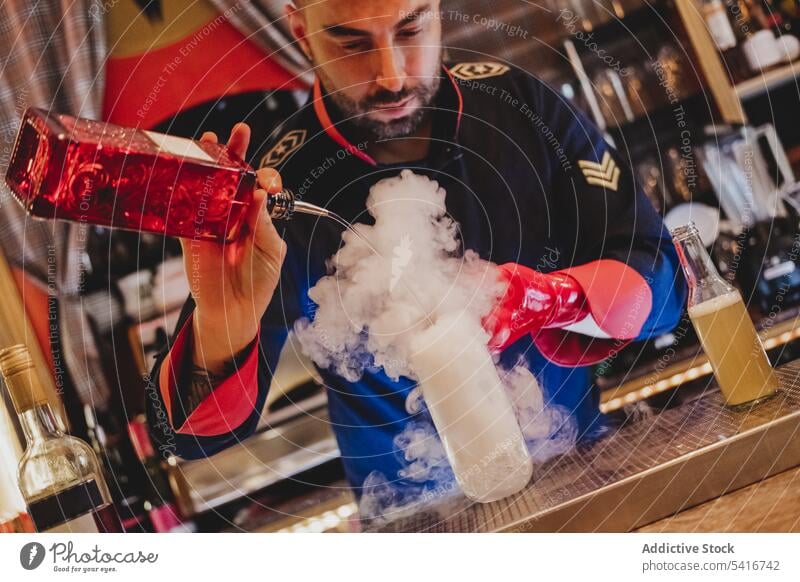 Bartender in red gloves making smoking cocktail bartender alcohol pouring nightclub stirring preparing mixing bottle barman uniform ice cubes glass drink