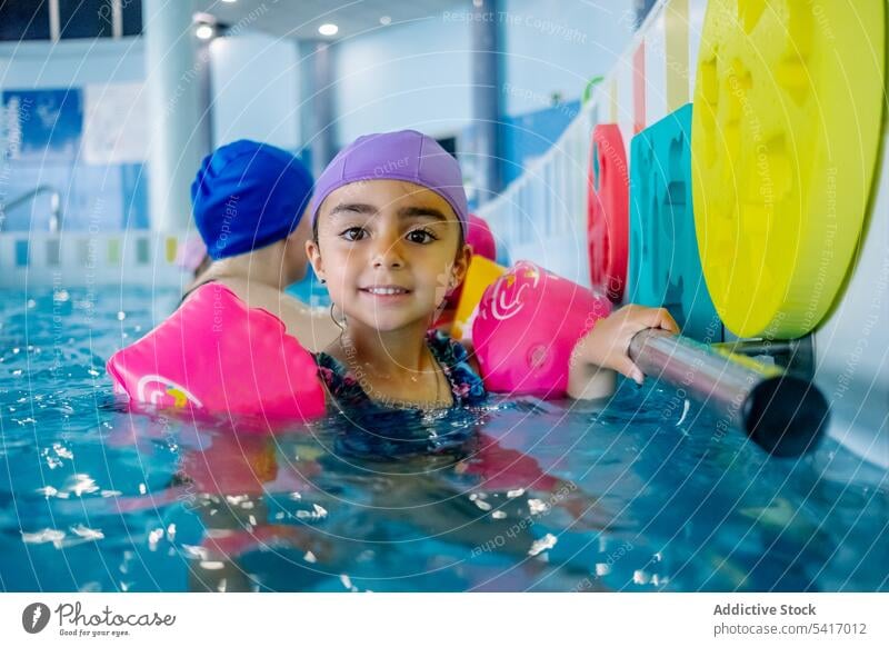 Ethnic girl with water wings in swimming pool playing park inflatable ethnic toy fun child kid joy happy little vacation rest relax leisure armbands activity