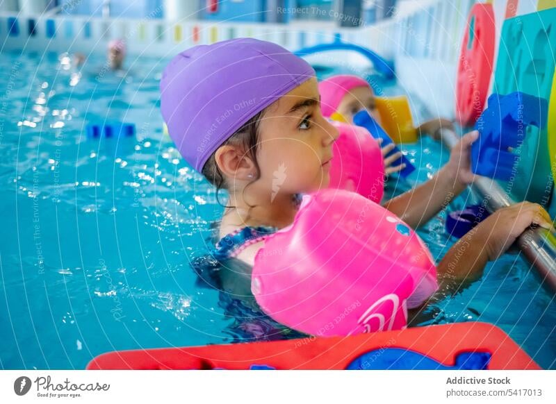 Ethnic girl with water wings in swimming pool playing park inflatable ethnic toy fun child kid joy happy little vacation rest relax leisure armbands activity