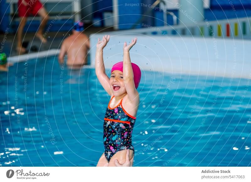 Wet girl standing on poolside wet looking away swimming hat goggles swimwear ethnic little kid child water park drops swimsuit leisure rest relax resort joy fun