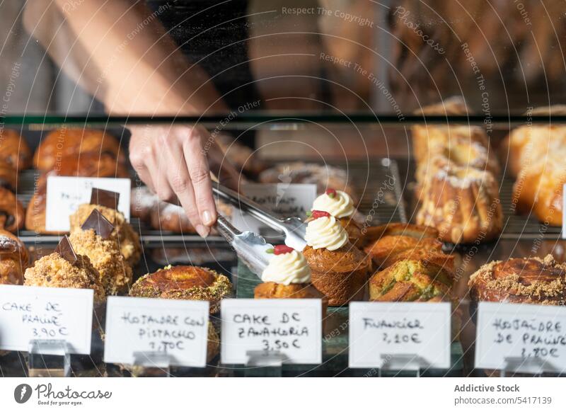 Assortment of delicious cakes on glass counter pastry dessert hand bakery sweet cafe confectionery french adult person holding taking serving fresh tasty yummy