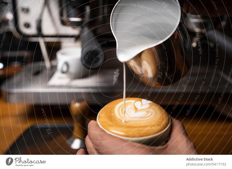 Barista making coffee with latte art barista cappuccino cup hand foam beverage pattern cafe occupation adult person professional pouring decorating hot milk