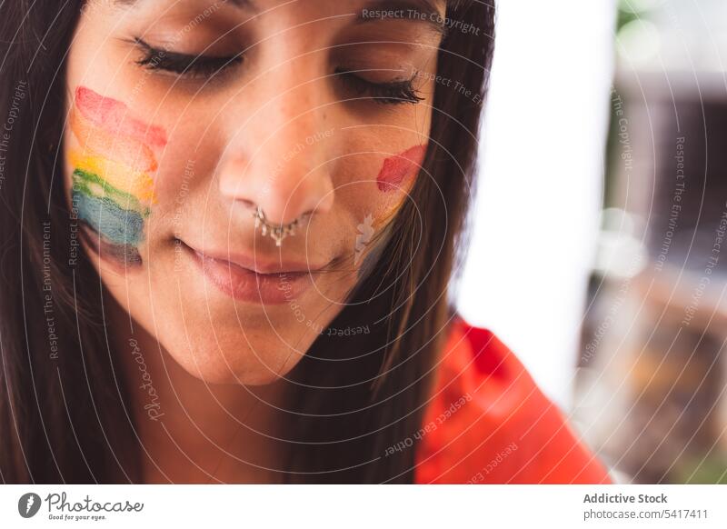 Brunette woman with LGBT symbol on face straightening hair beautiful lgbt attractive young pretty sensual freedom equality rights cheerful female tolerance