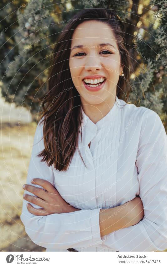 Confident young lady standing in park woman confident smiling crossed arms lifestyle leisure sunny daytime female stylish trendy blouse cheerful glad pleased