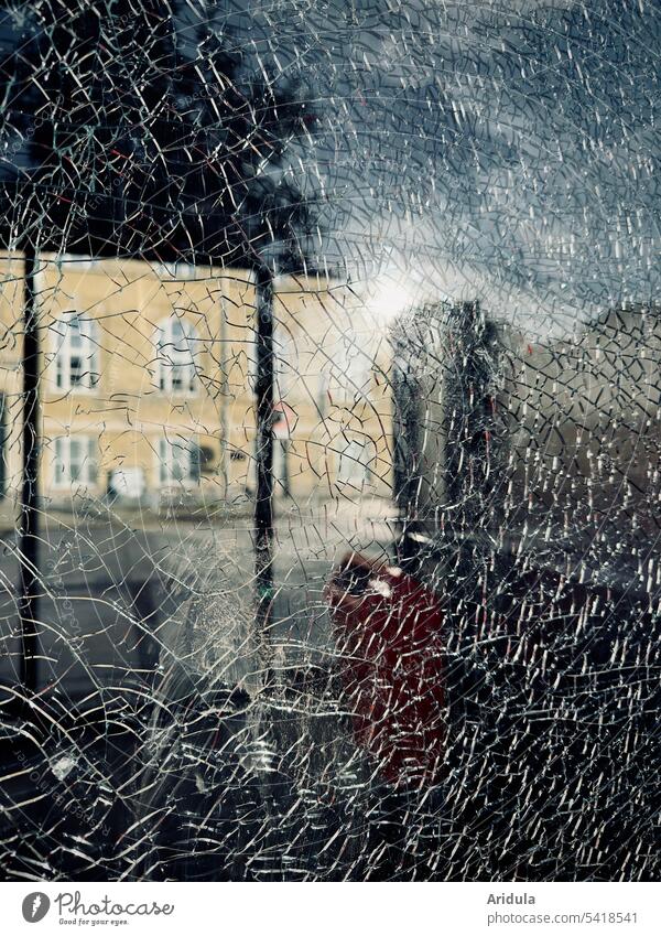 Cracks in a glass wall with a view of a yellow old building, a tree and the blue sky reflected in the glass pane Pane Glass wall Broken Window cracks