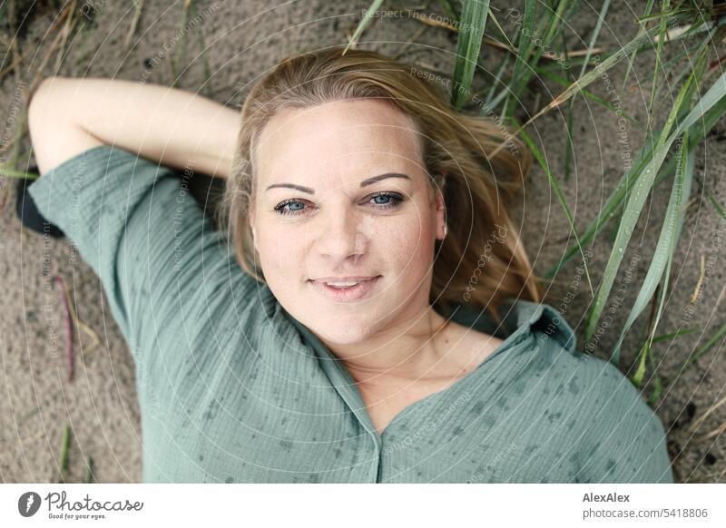 Portrait of beautiful blonde woman lying in the sand on the beach and smiling at the camera Woman pretty Blonde Long-haired Blonde hair Joy Smiling Beach Sand