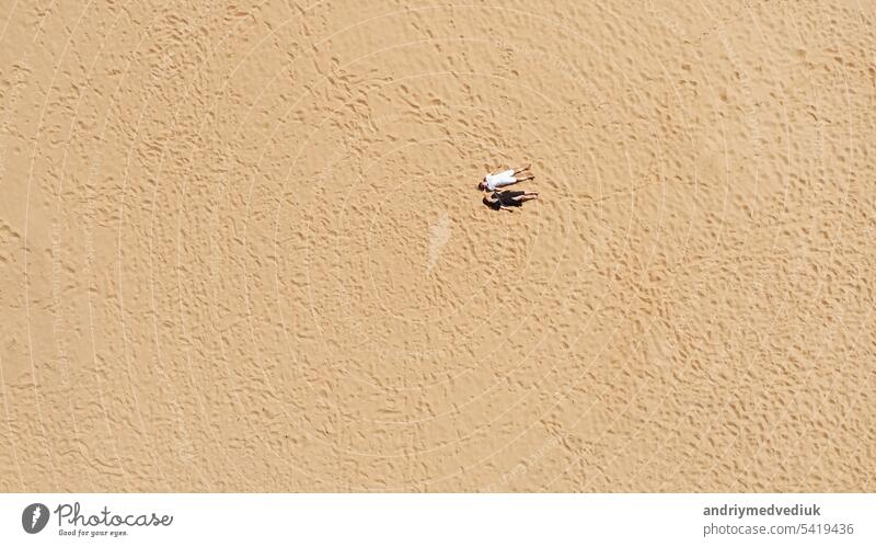 Aerial view of a young couple lying on the white sand. man and woman spend time together and travel through the desert aerial beach vacation turquoise nature