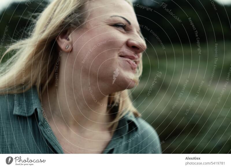 side portrait of beautiful blonde woman in motion against a background of trees and grass Woman pretty Blonde Long-haired Blonde hair Joy Smiling Sand