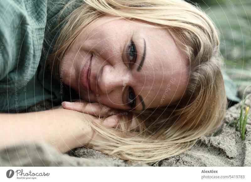 Portrait of beautiful blonde woman lying in the sand on the beach and smiling sideways at the camera Woman pretty Blonde Long-haired Blonde hair Joy Smiling