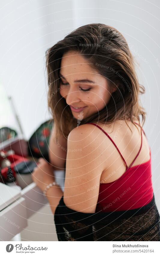 Sensual smiling woman in red and black outfit using fan. Spanish vacation. Passionate romantic female portrait in boudoir room. Summer heatwave.