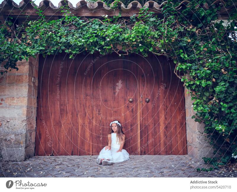 Little girl sitting near huge wooden door rest child relax beautiful little adorable kid cute female innocence pensive purity individuality comely sweet hair