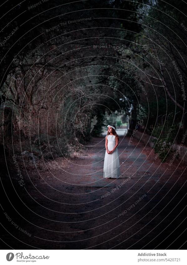 Little girl walking alone in dark alley child mystery dusk lonely forest walkway female road pavement tree vegetation evening standing park small beautiful