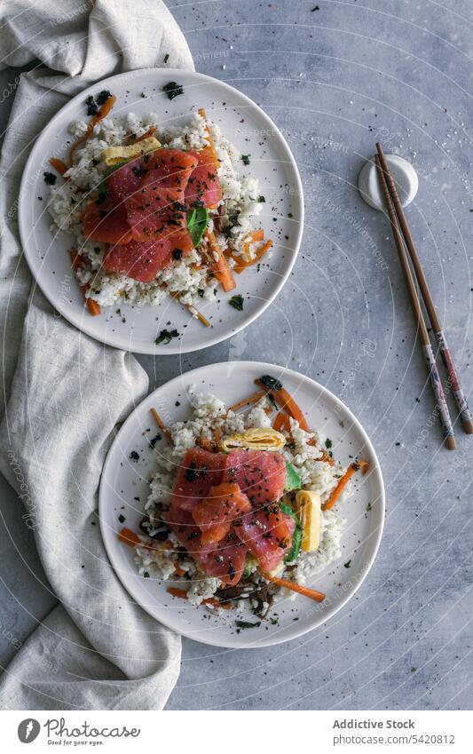 Tasty crumbly rice with salmon and vegetables on linen with chopsticks on table dish asian food meal poke fresh healthy fish appetizer tasty cuisine culinary