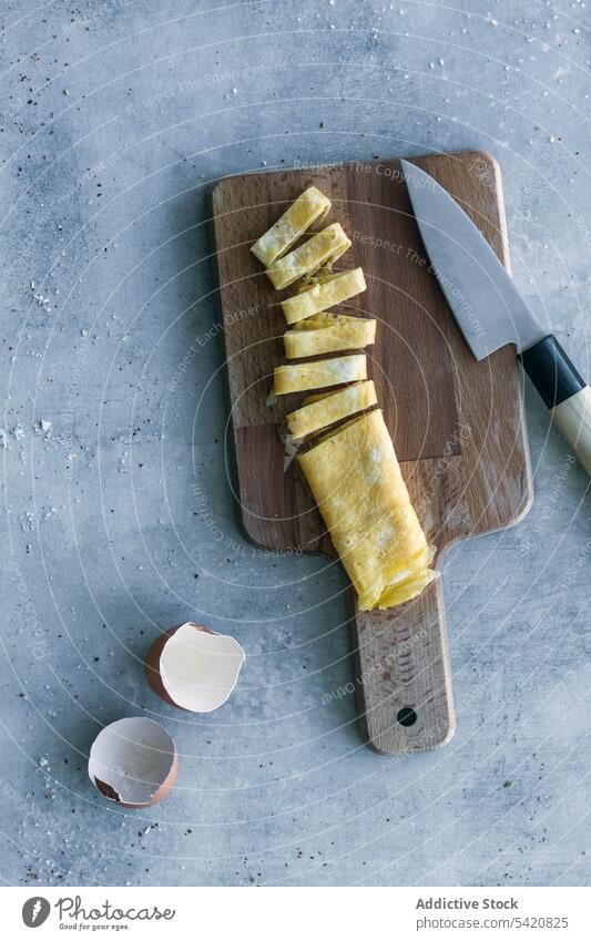 Sliced ??egg omelet on cutting board on table fresh roll food knife wooden eggshell meal fried breakfast eating healthy lunch dinner snack cuisine gourmet roast