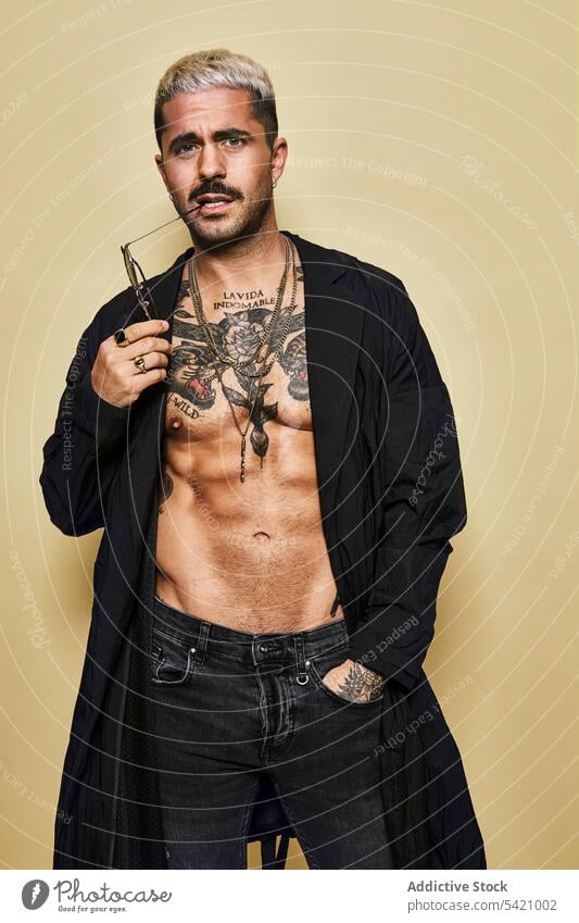 Provocative shirtless man in black coat sunglasses macho cool trendy brutal tattoo style fashion unshaven model personality muscular jeans beard male ethnic