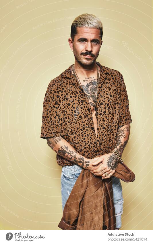 Trendy ethnic guy in stylish outfit standing in studio man trendy style fashion leopard coat model jeans beard male cloth modern cool confident handsome