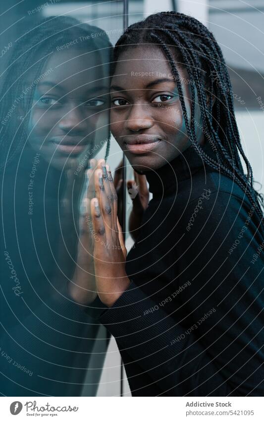 Positive black female leaning on glass wall woman street city positive ethnic urban casual reflection glad modern building model african american lifestyle