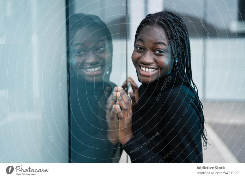 Positive black female leaning on glass wall woman street city positive ethnic urban casual reflection glad modern building model african american lifestyle