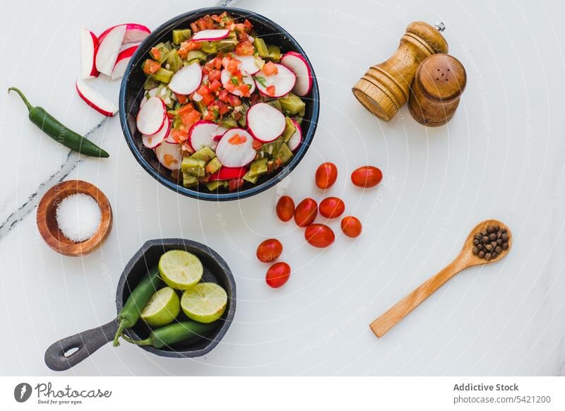 Mixed salad with radish around ingredients on white background vegetable mix jalapeno kitchen vegetarian seasoning tomato cherry spicy condiment pepper lime