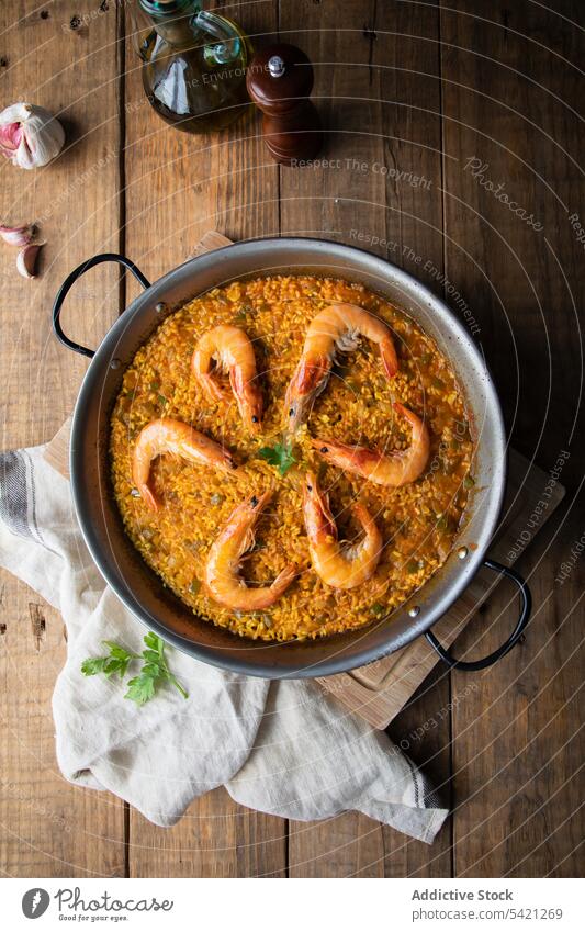 Large pan of savory rice dish with aromatic yummy fried prawns on wooden table paella shrimp towel roasted food rustic culinary homemade nutrition fresh