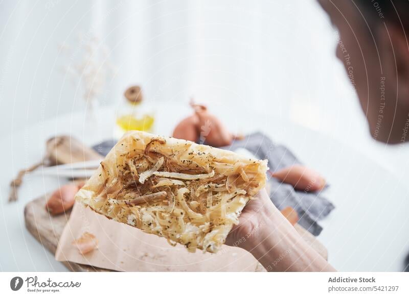 Crop person taking piece of puff pastry with onion and cream cheese ingredient cutting board rustic tradition meal cuisine fresh homemade delicious cook food