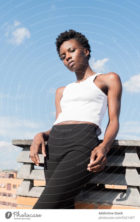 Stylish black female model standing graciously on rooftop woman style appearance confident outfit cool glamour calm slender positive serene unemotional sensual