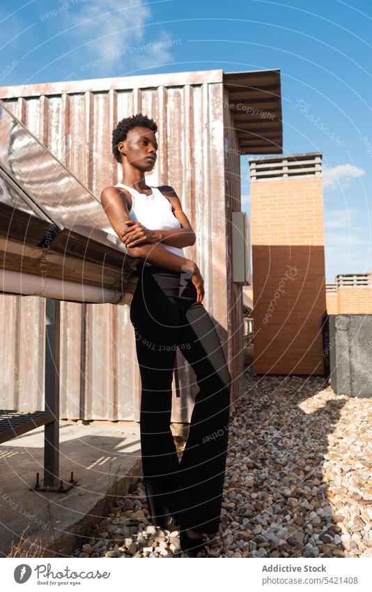 Stylish black female model standing graciously on rooftop woman style appearance confident outfit cool glamour calm slender positive serene unemotional sensual