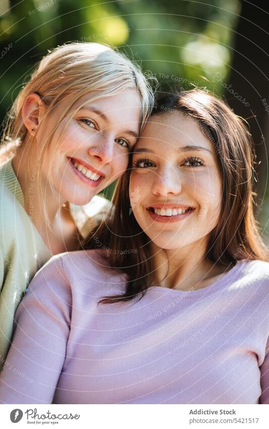 Charming teenage sisters looking at camera in park tender charming appearance together delicate girl garden nature summer sunny sunlight enjoy carefree harmony