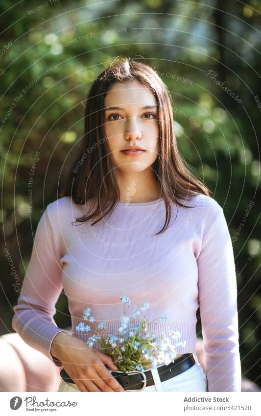 Tender teen girl with flowers in jeans looking at camera teenage tender wildflower summer garden delicate serene bloom plant flora harmony summertime tranquil