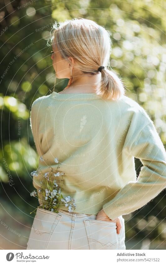 Unrecognizable teen girl with flowers in jeans pocket tender summer wildflower park teenage gentle nature stand bloom style blossom flora season carefree