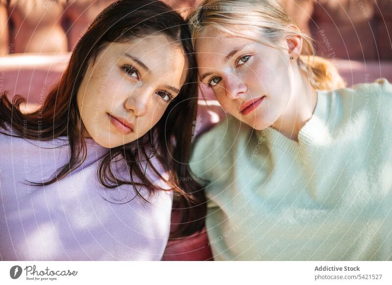 Delicate teenage sisters sitting near sofa in garden tender sibling bonding charming serene relax rest together couch friend friendship friendly delicate gentle