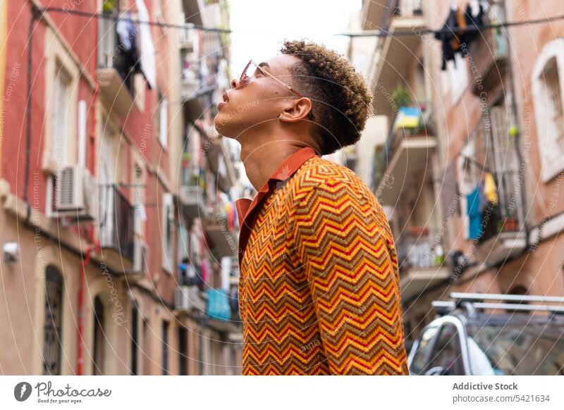 Stylish ethnic man walking on city street style traveler urban confident listen trendy explore male young hispanic tourist vacation lifestyle colorful tourism