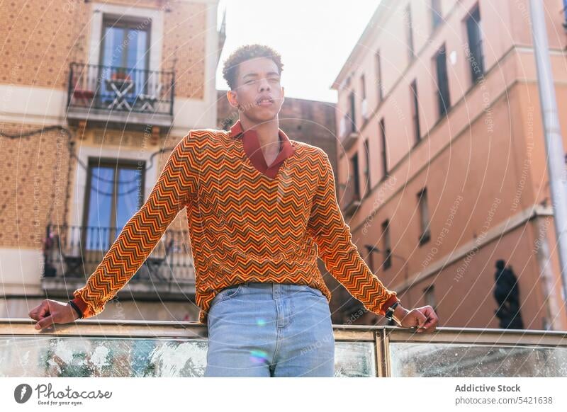 Thoughtful stylish ethnic man in colorful shirt style trendy thoughtful fashion pensive stripe outfit modern young male curly hair afro confident handsome